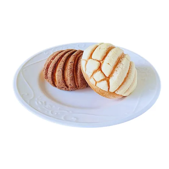Two mini vegan conchas, vanilla and cocoa, on a white plate